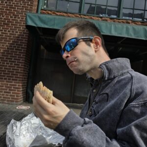 Photo : Gabriel mange un sandwich en terrasse au marché Saint Lawrence